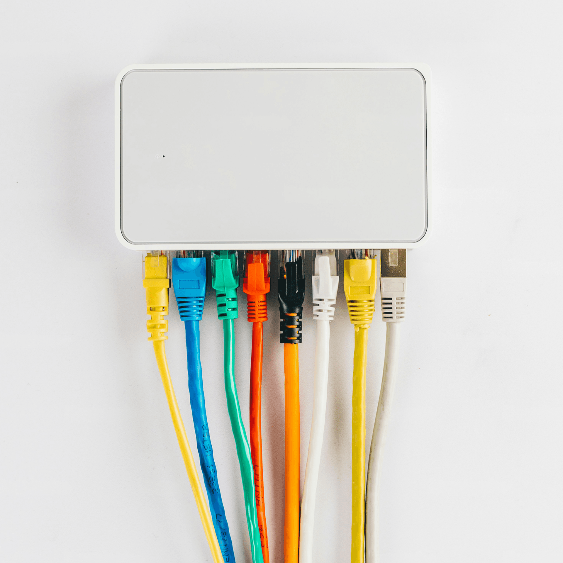 A photograph of a white network switch with multiple coloured Ethernet cables plugged into its ports against a plain white background.