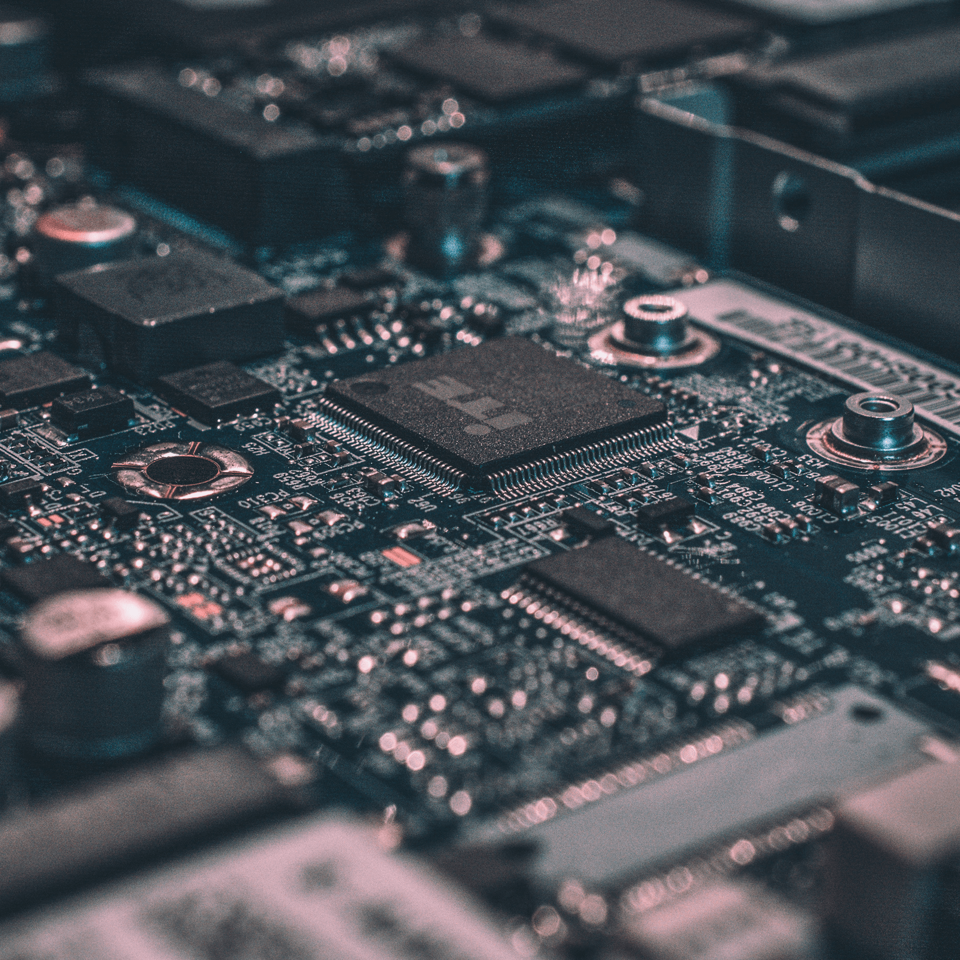 Close-up photo of a computer circuit board, showing a central microchip, electronic components, and metallic connectors.